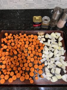 Chopped onion, carrots, ginger, garlic. Prep to make roasted carrot soup.